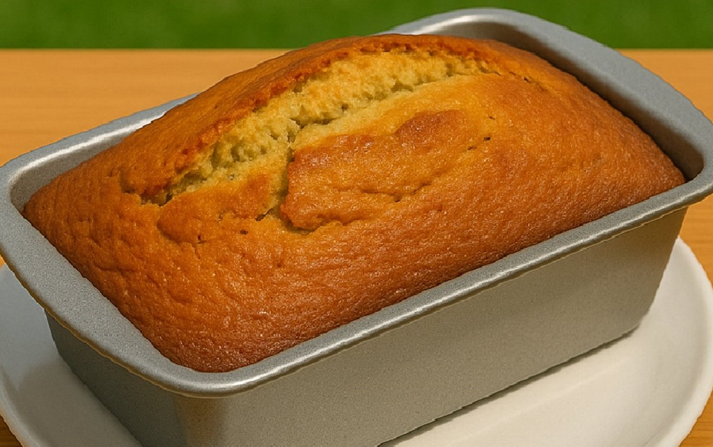 Sliced moist banana bread on a wooden board with ripe bananas in background