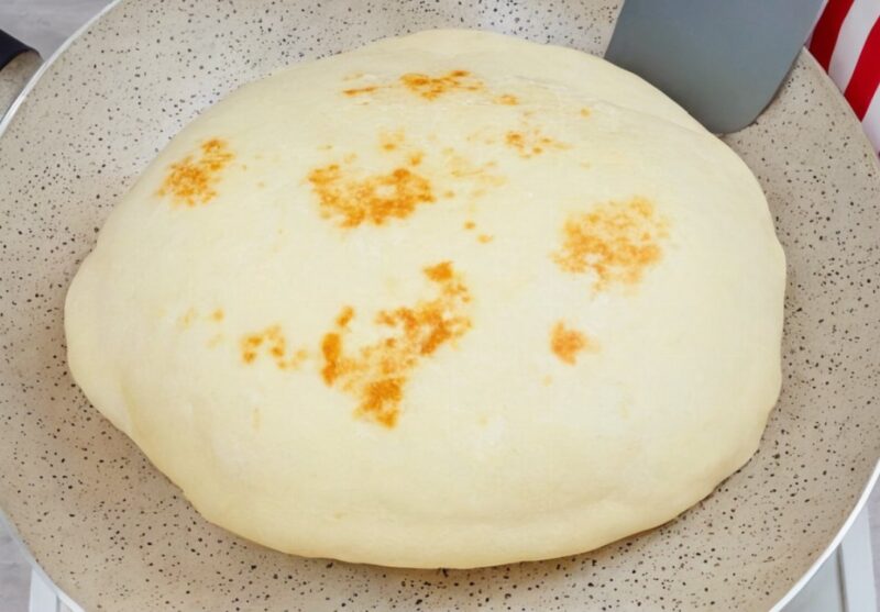 Homemade naan bread on a hot skillet with melted butter