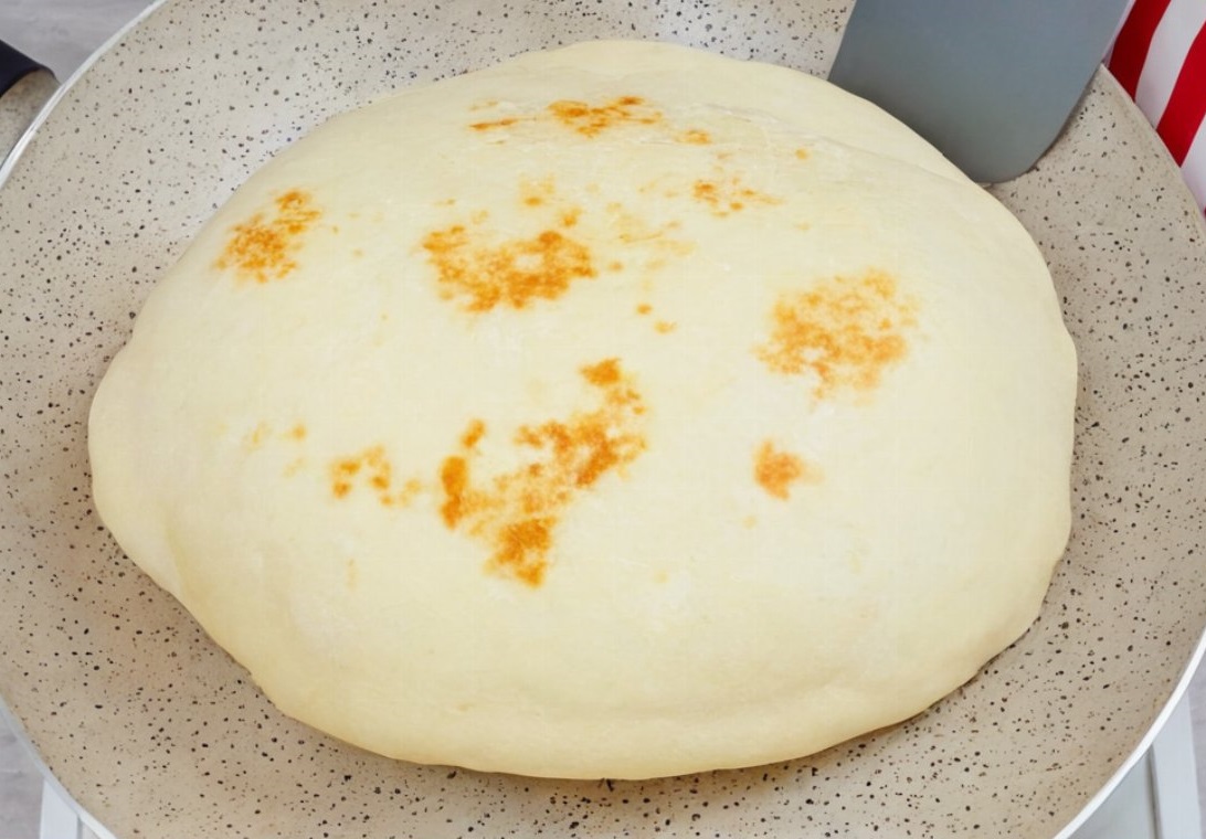 Homemade naan bread on a hot skillet with melted butter
