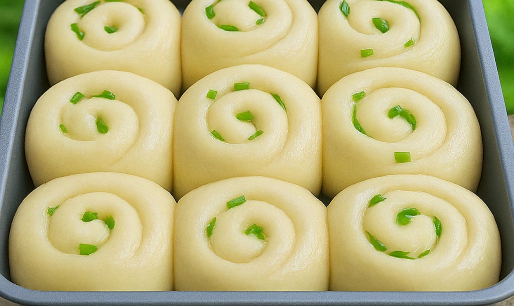 Stack of golden milk buns on a wooden board with a soft interior crumb