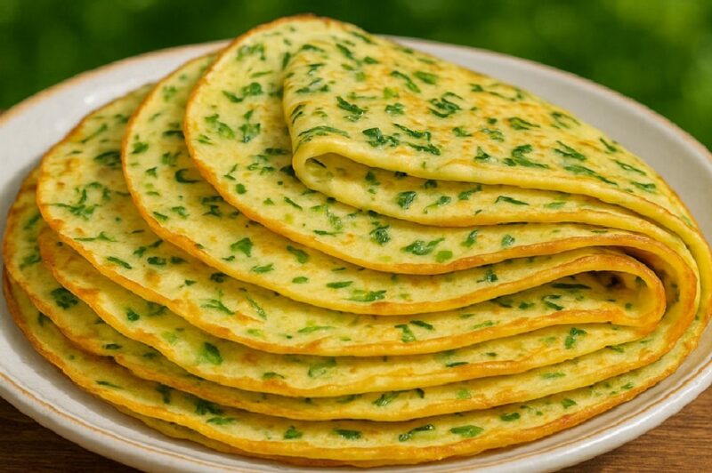 Golden zucchini and potato pancakes stacked on a plate with fresh herbs